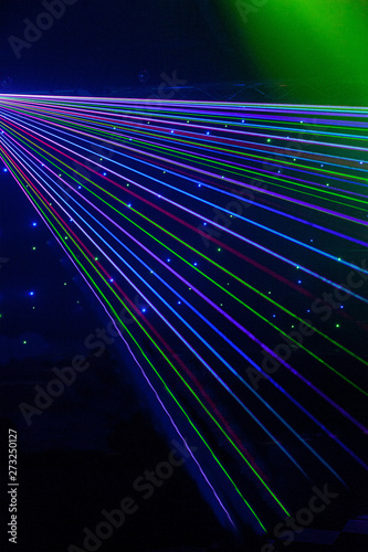 Bright nightclub red, green, purple, white, pink, blue laser lights cutting through smoke machine smoke making light patterns on the dance floor with bokeh in the background. Mardi Gras inspiration