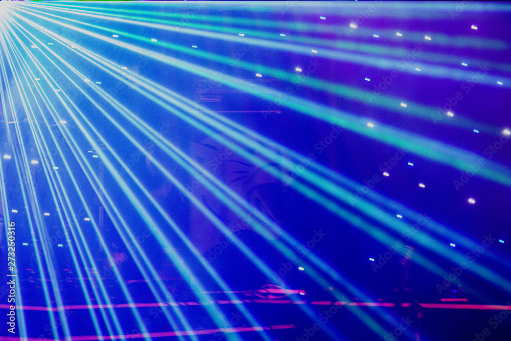 Bright nightclub purple, white, blue laser lights cutting through smoke machine smoke making light and rainbow patterns on the dance floor with bokeh in the background. Mardi Gras Bright nightclub purple, white, blue laser lights cutting through smoke machine smoke making light and rainbow patterns on the dance floor with bokeh in the background. Mardi Gras