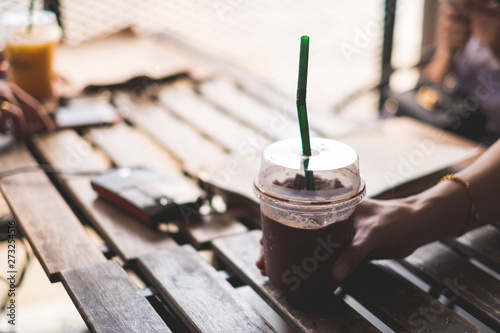 selective focus chocolate smoothie hold by woman hand on wooden table