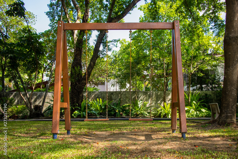 Swing set on courtyard surrounded with trees in the park