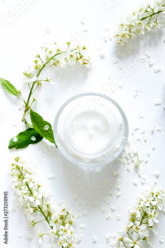 Jar with cream and flowers on white background. Beauty blogger flat lay concept.Woman's skincare routine. Daily face cream.Place for your text or logo.