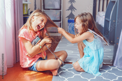 Two little mad angry girls sisters having fight at home. Friends girls can not share toy bag. Lifestyle authentic funny family moment of siblings quarrel. Kids bad behaviour.