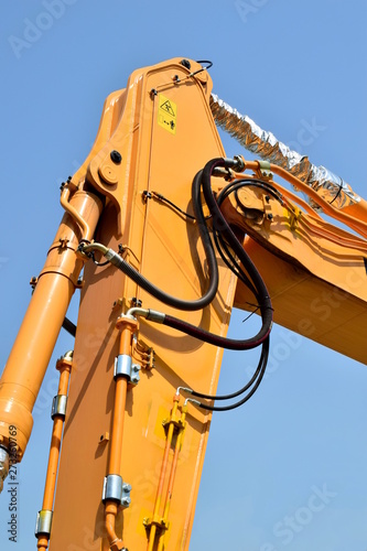 Manipulator crane with hydraulic cylinder. Working equipment of logging equipment. Close-up of the crane fragment. Against the blue sky.