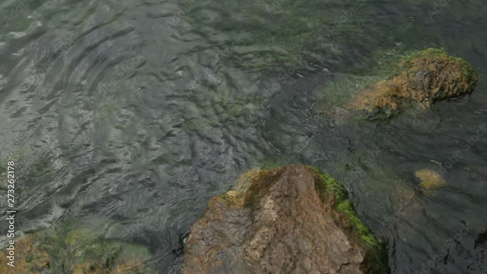 Blue water and textured foam at the stone shore. Texture of waves and sea water from above. Blue water and textured foam at the stone shore. Texture of waves and sea water from above.