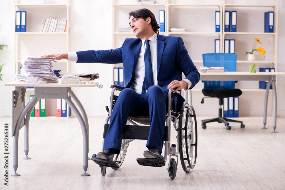 Young male employee in wheelchair working in the office Young male employee in wheelchair working in the office