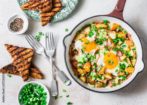 Bilde på lerret Potatoes, ham, eggs breakfast hash in a frying pan on a light background, top view