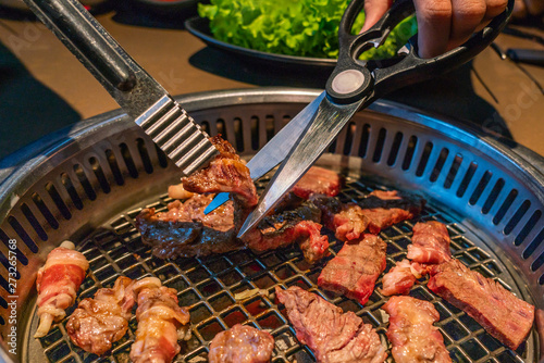 Cutting grilled beef slices on coal stove at Japanese restaurant photo