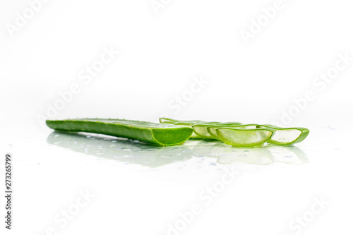 isolated on a white  sprinkled water background  a leaf of aloe  next to it slices with fresh aloe vera pulp