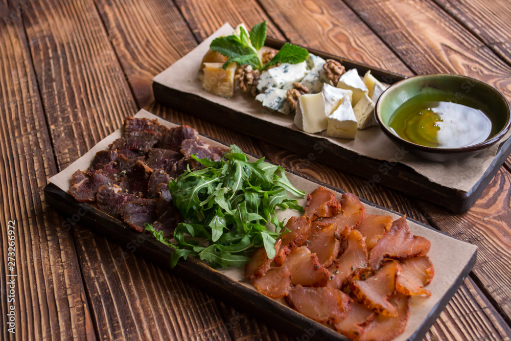 Cheese and meat plate on a wooden background.