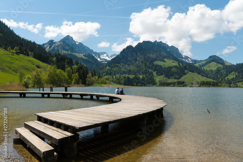 two men best friends enjoy the summer lakeside view at the Schwarzsee Lake in the Swiss Alps in canton Fribourg