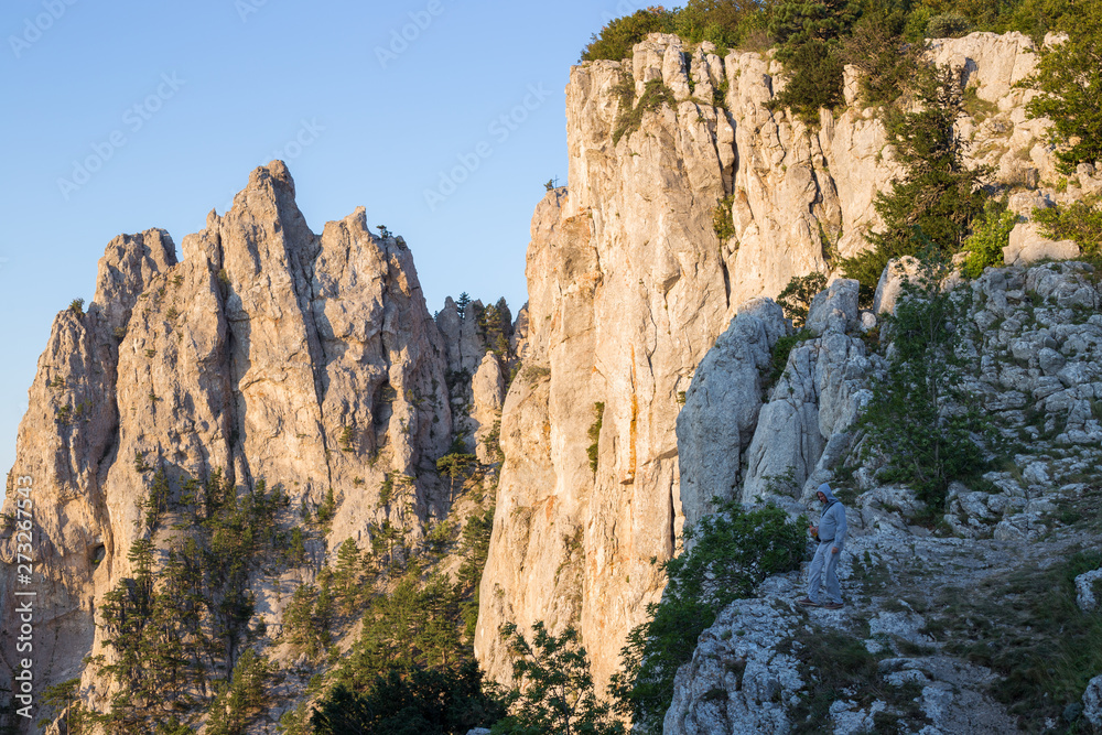 on a cliff of Ai-Petri mountain in Crimea lit by the sun at dawn, there is a man