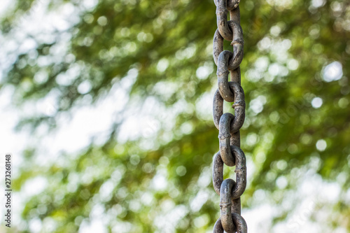 iron old hanging chain on unfocused blurred bokeh effect green park outdoor natural background, copy space