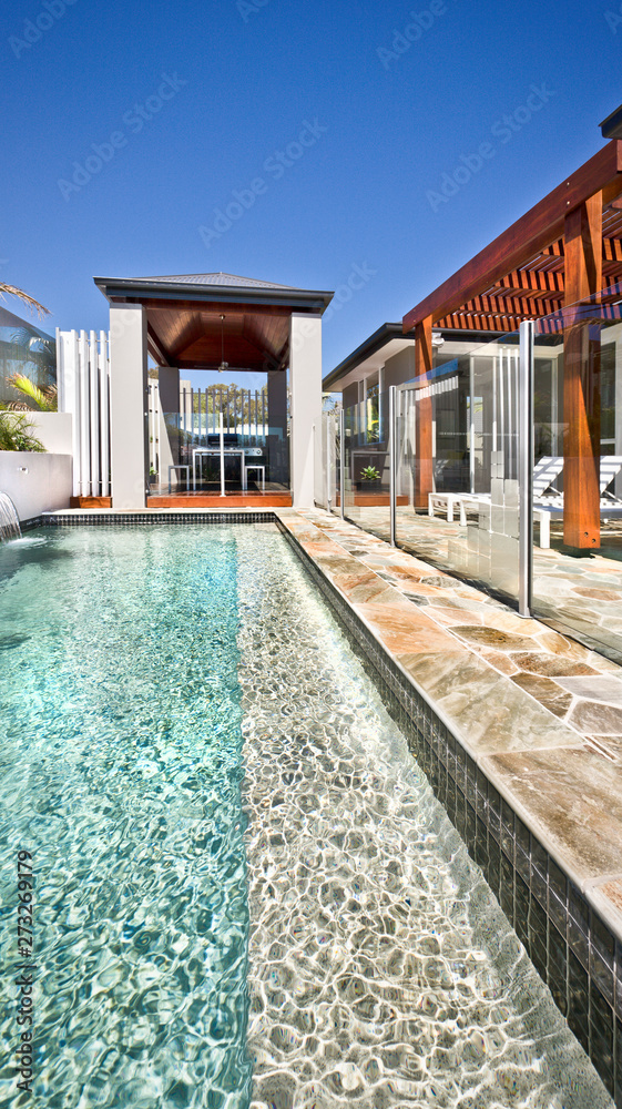 Modern swimming pool with outdoor patio area and wooden pillars