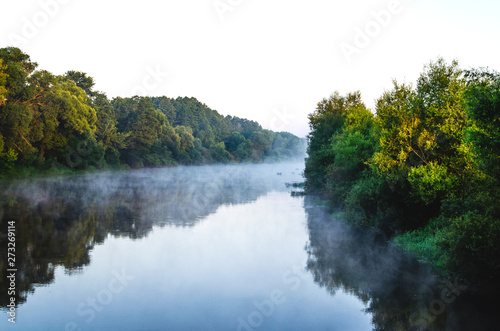 The mist rises above the river. Cold early summer morning.