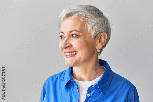 Positive human facial expressions, emotions, feelings and reaction. Profile of good looking fashionable European female wearing blue shirt and stylish pixie hairdo laughing at good funny joke