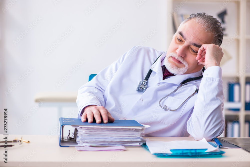 Fototapeta premium Old male doctor working in the clinic 