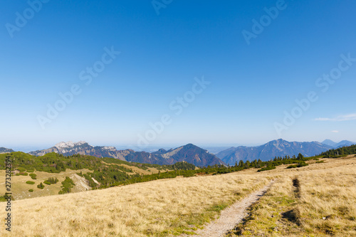 Rolling Hills on Mountain Range near Mountain Geigelstein, Schleching, with dry grass, Mountains Kampenwand, Hochplatte, Hochfelln and Hochgern in background