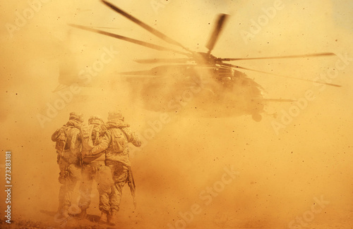 Obraz na plátně 2 soldiers helping wounded soldier between dust in battle field to board the hel