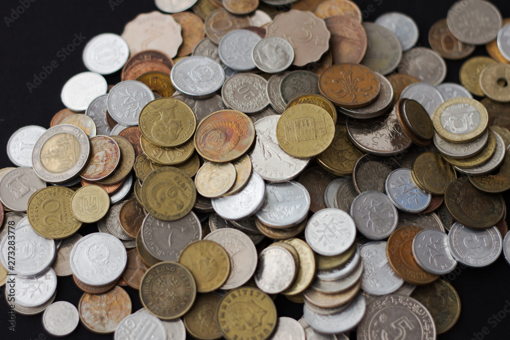 A pile of coins from different countries on a black background A pile of coins from different countries on a black background