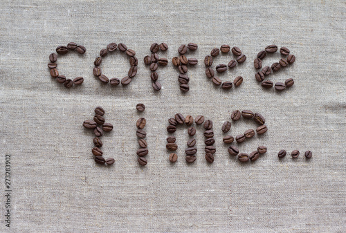 Inscription Coffee Time of a roasted coffee beans on a grey canvas, table, top view