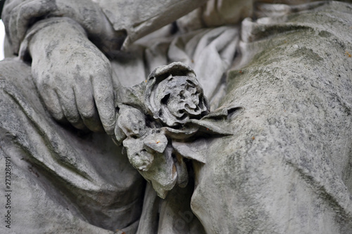 A sandstone statue of an angel with a broken rose in her hand on a cemetery in Berlin-Germany. photo