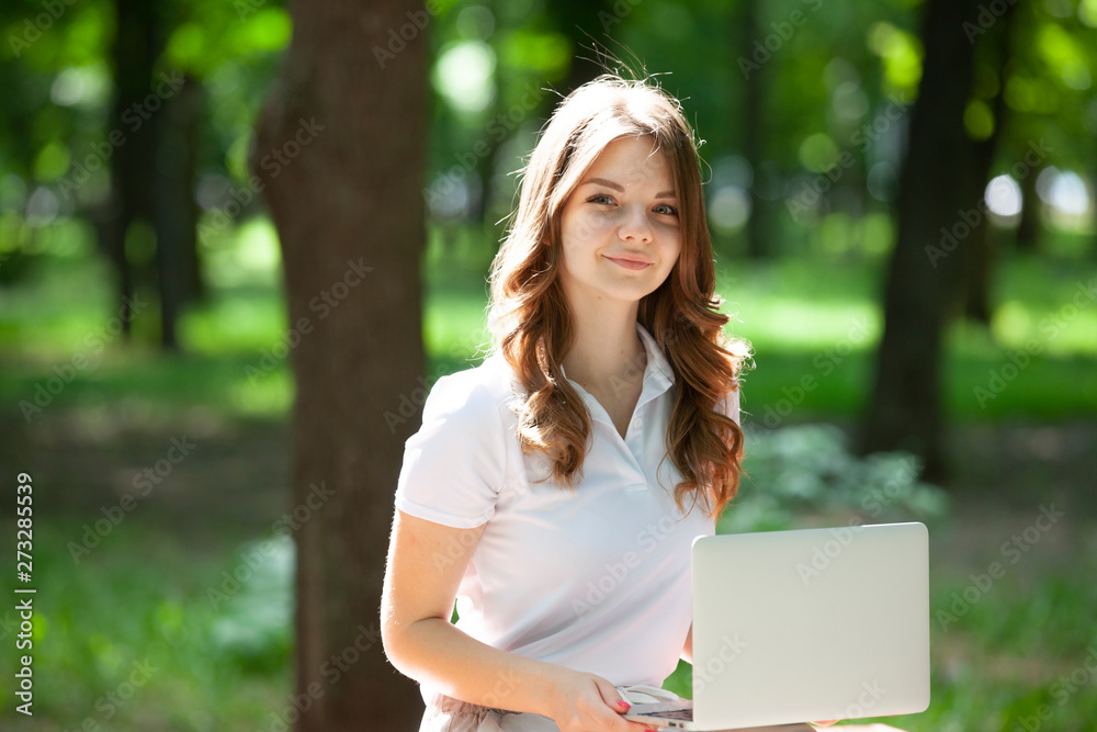Beautiful young woman using laptop in a park.