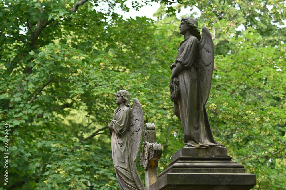 Two sandstone sculptures of angels in front of a crypt entrance. Two sandstone sculptures of angels in front of a crypt entrance.