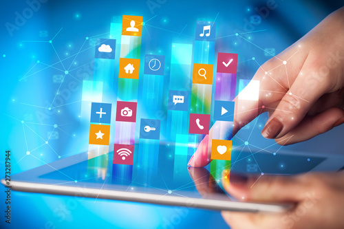 Billede på lærred Businessman hand using tablet with flying application icons around