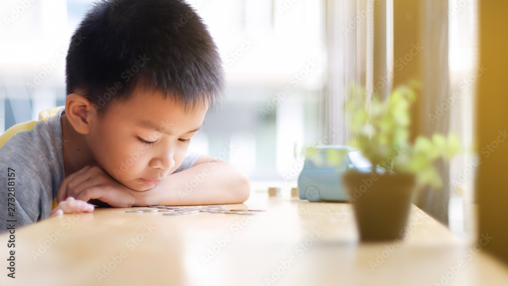 Young boy looking at a coins sorting,scattering on the table.Kid's ambition of being rich.Young boy sorting,grouping his coins on the table. Young boy looking at a coins sorting,scattering on the table.Kid's ambition of being rich.Young boy sorting,grouping his coins on the table.