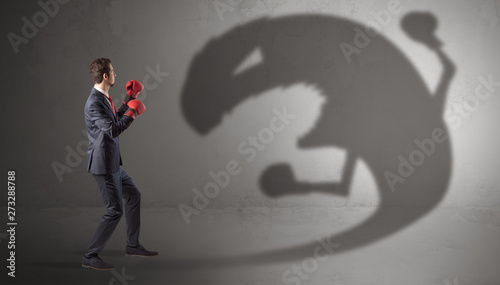 Businessman with boxing glove fighting with a big monster shadow 