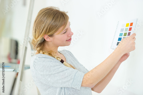 woman choosing color for wall from swatches in room