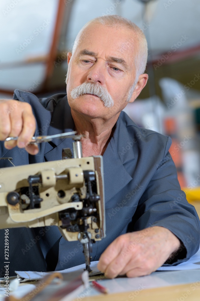 elderly man cutting thread of sewing machine