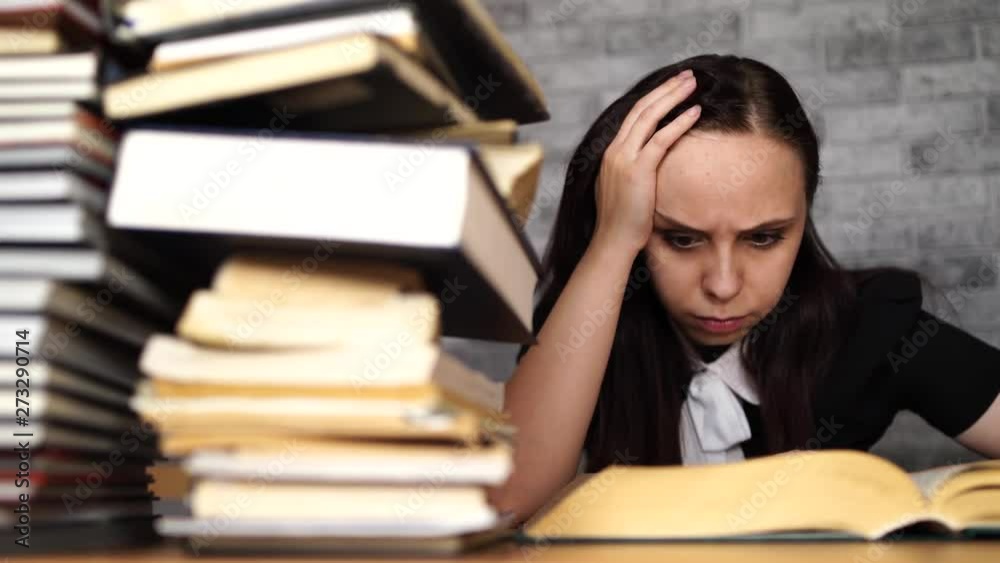 Woman student boring reading book at library with a lot of books in university. Woman student boring reading book at library with a lot of books in university.