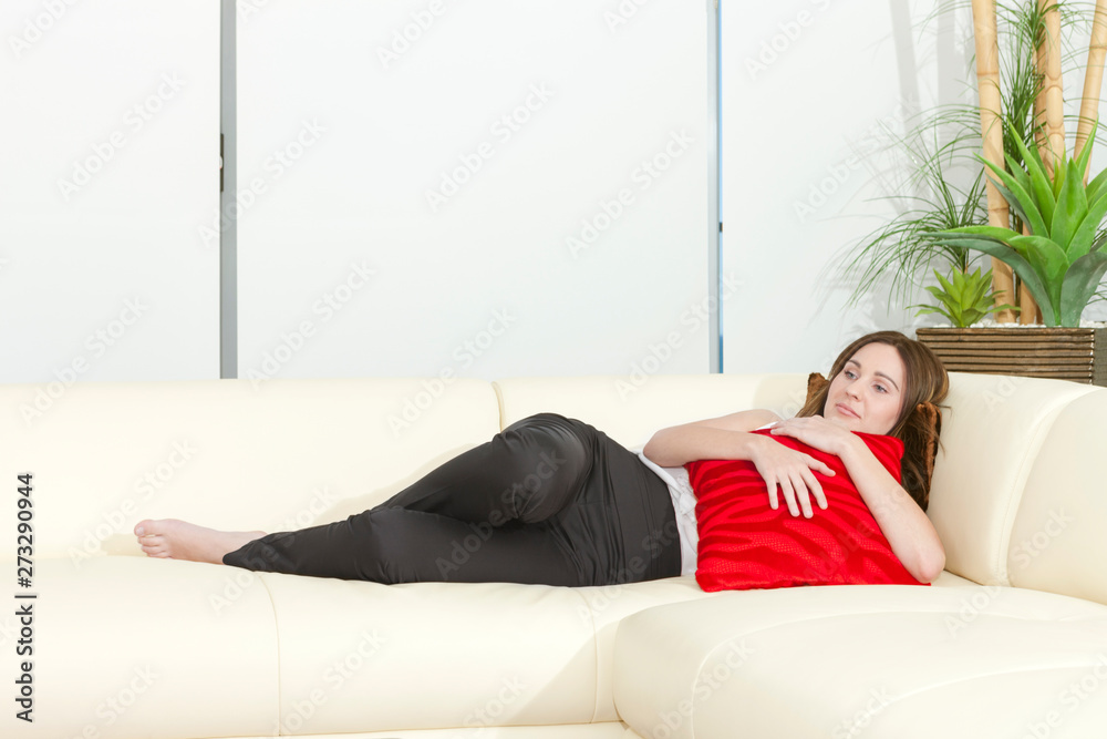 Woman laying on a couch and hugging a cushion Woman laying on a couch and hugging a cushion