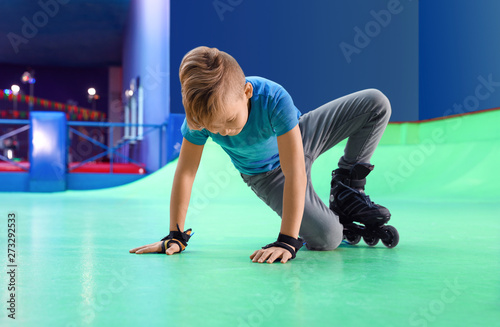 Boy falling down at roller skating rink