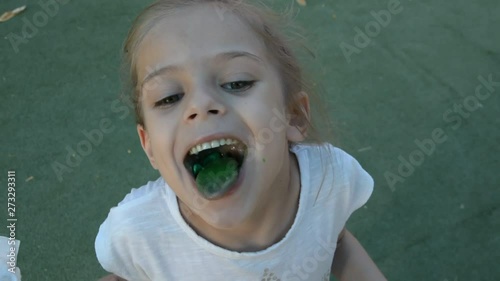 smiling little girl with green tongue from lollypop