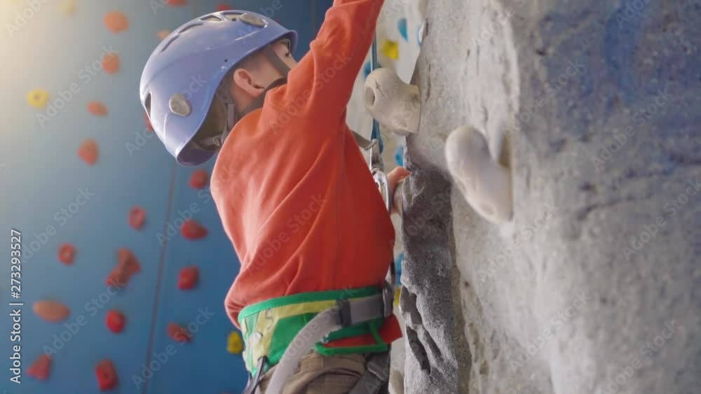 fitness, extreme sport, people and healthy lifestyle concept - little boy exercising at indoor climbing gym wall