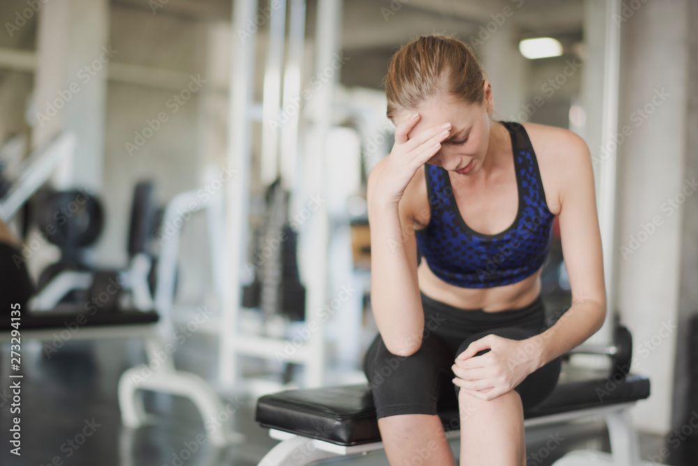 Young Woman have muscle pain at knee while workout at gym. Woman headache. Accident weight training at fitness, muscle pain concept. Young Woman have muscle pain at knee while workout at gym. Woman headache. Accident weight training at fitness, muscle pain concept.