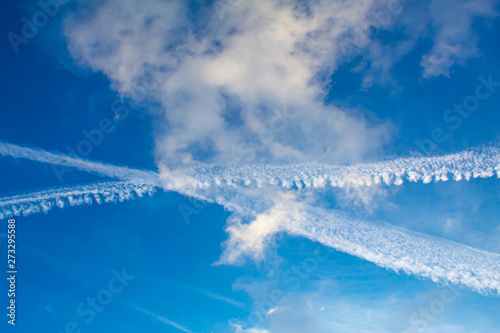 Obraz na płótnie Blue sky with visible contrails of two crossing airliners. w salonie