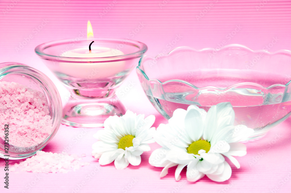 wellness, spa and body care concept with pink candle, fresh water, white daisy flower over pink background wellness, spa and body care concept with pink candle, fresh water, white daisy flower over pink background