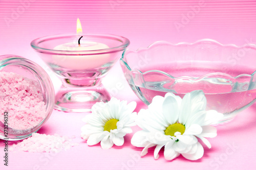 wellness  spa and body care concept with pink candle  fresh water  white daisy flower over pink background 