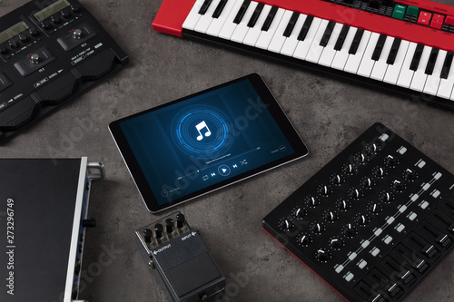 Playing song on tablet with electronic music instruments around
