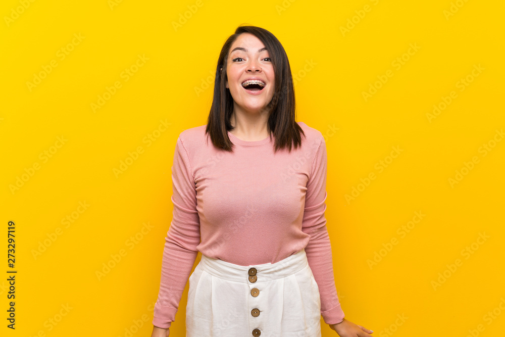 Young Mexican woman over isolated yellow background with surprise facial expression Young Mexican woman over isolated yellow background with surprise facial expression