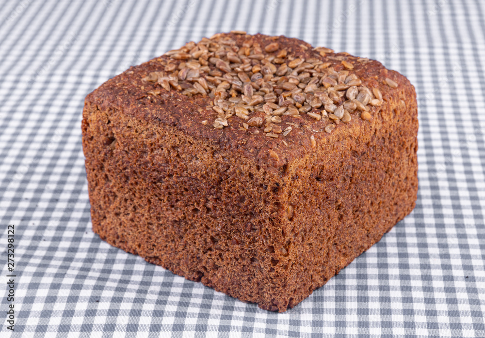 Piece of multigrain bread with sunflower seeds on top, on a blue table Piece of multigrain bread with sunflower seeds on top, on a blue table