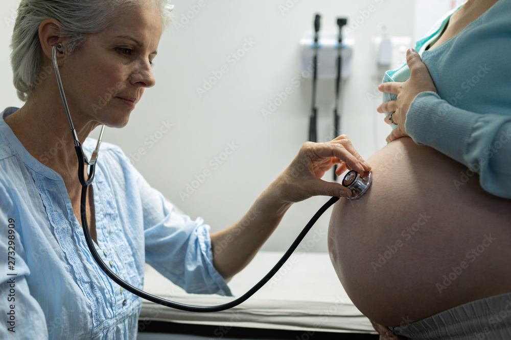 Doctor examining pregnant woman belly with stethoscope Stock Photo | Adobe  Stock