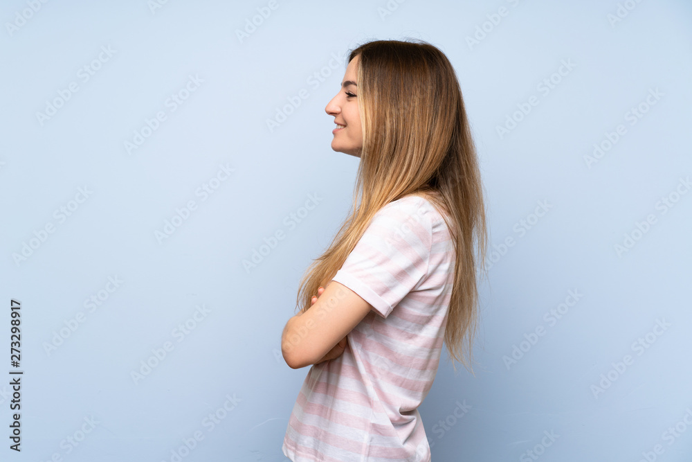 Young woman over isolated blue background in lateral position Young woman over isolated blue background in lateral position