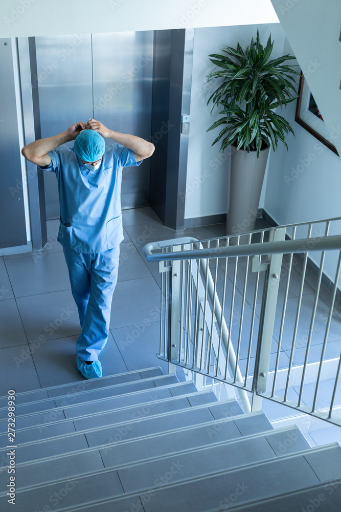 Male surgeon wearing surgical mask while standing at stairs