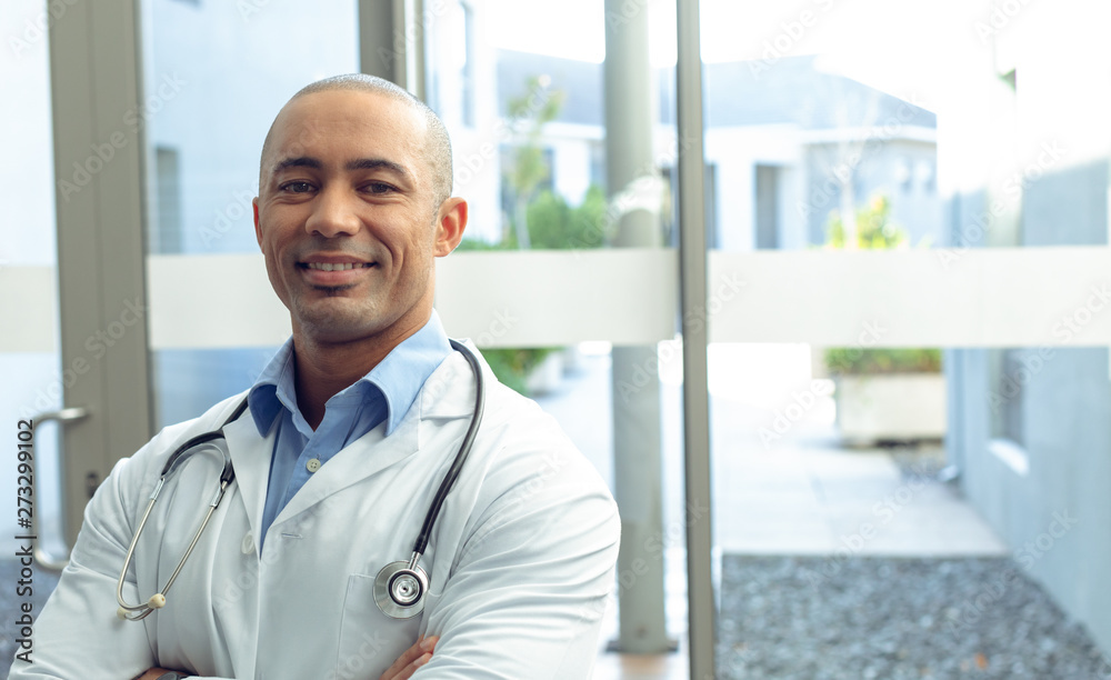 Male doctor with arm crossed looking at camera in hospital