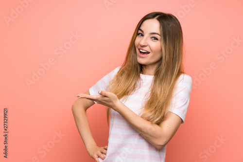 Young woman over isolated pink wall extending hands to the side for inviting to come