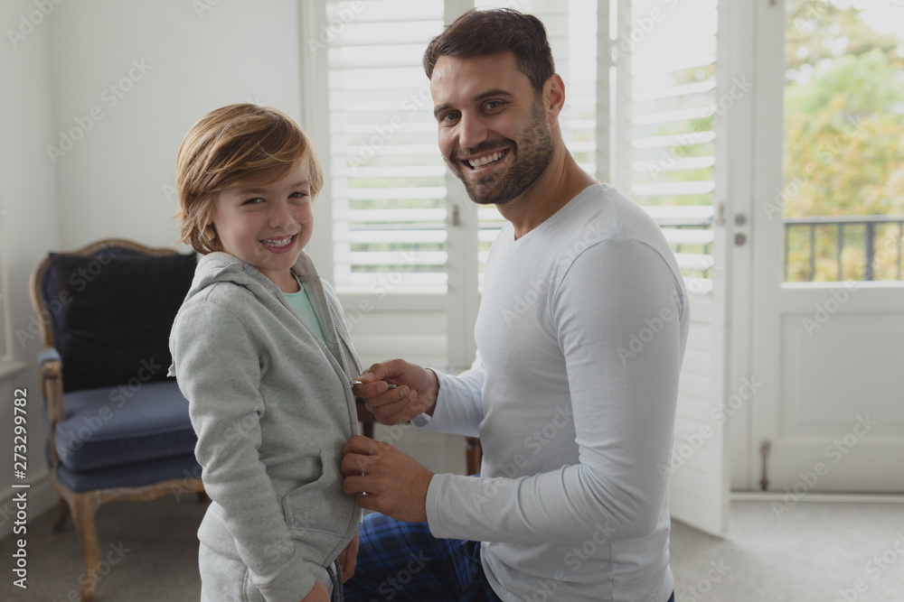 Fototapeta premium Father helping son putting on clothes 